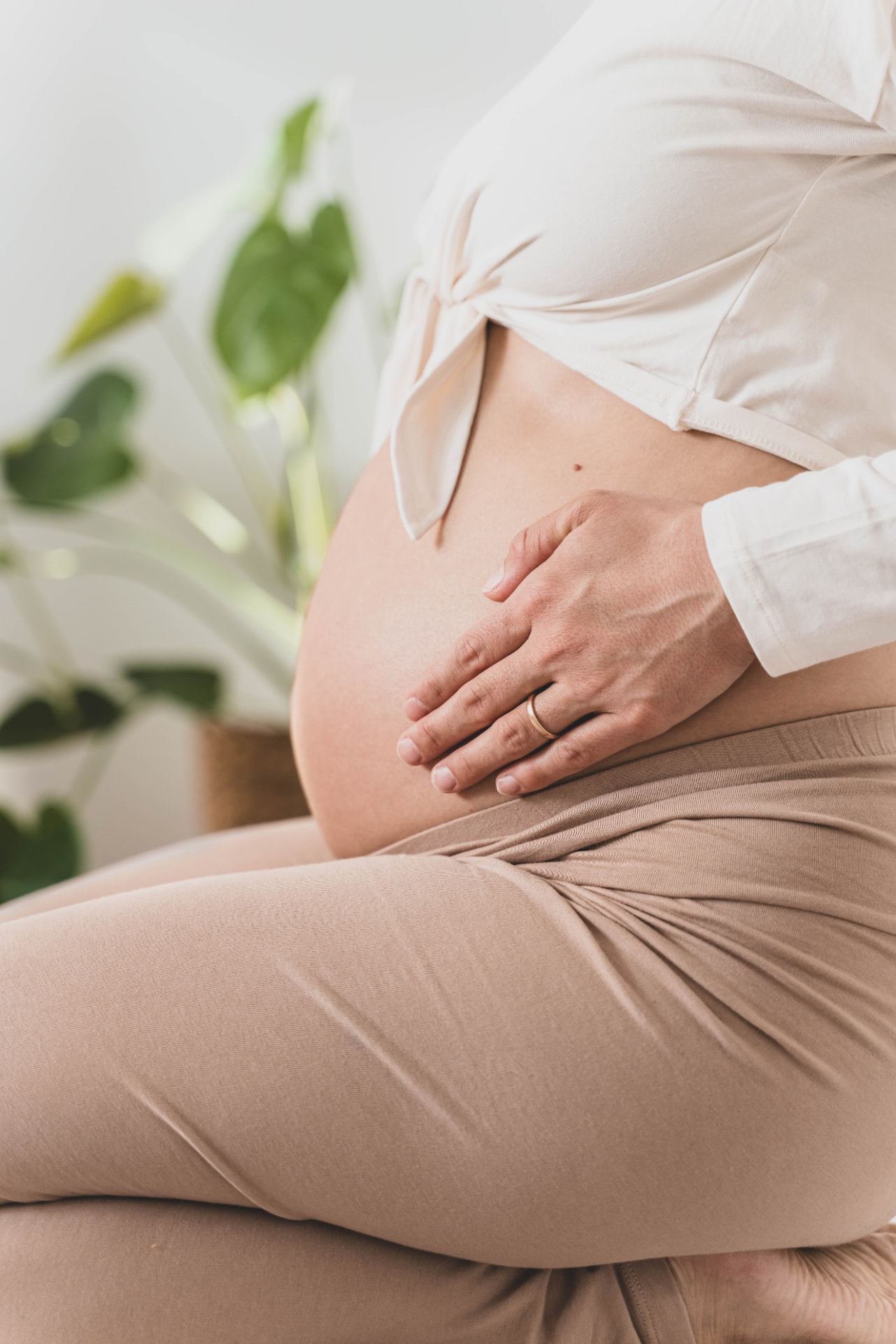 Expectant mother resting her hands on her belly in soft natural light